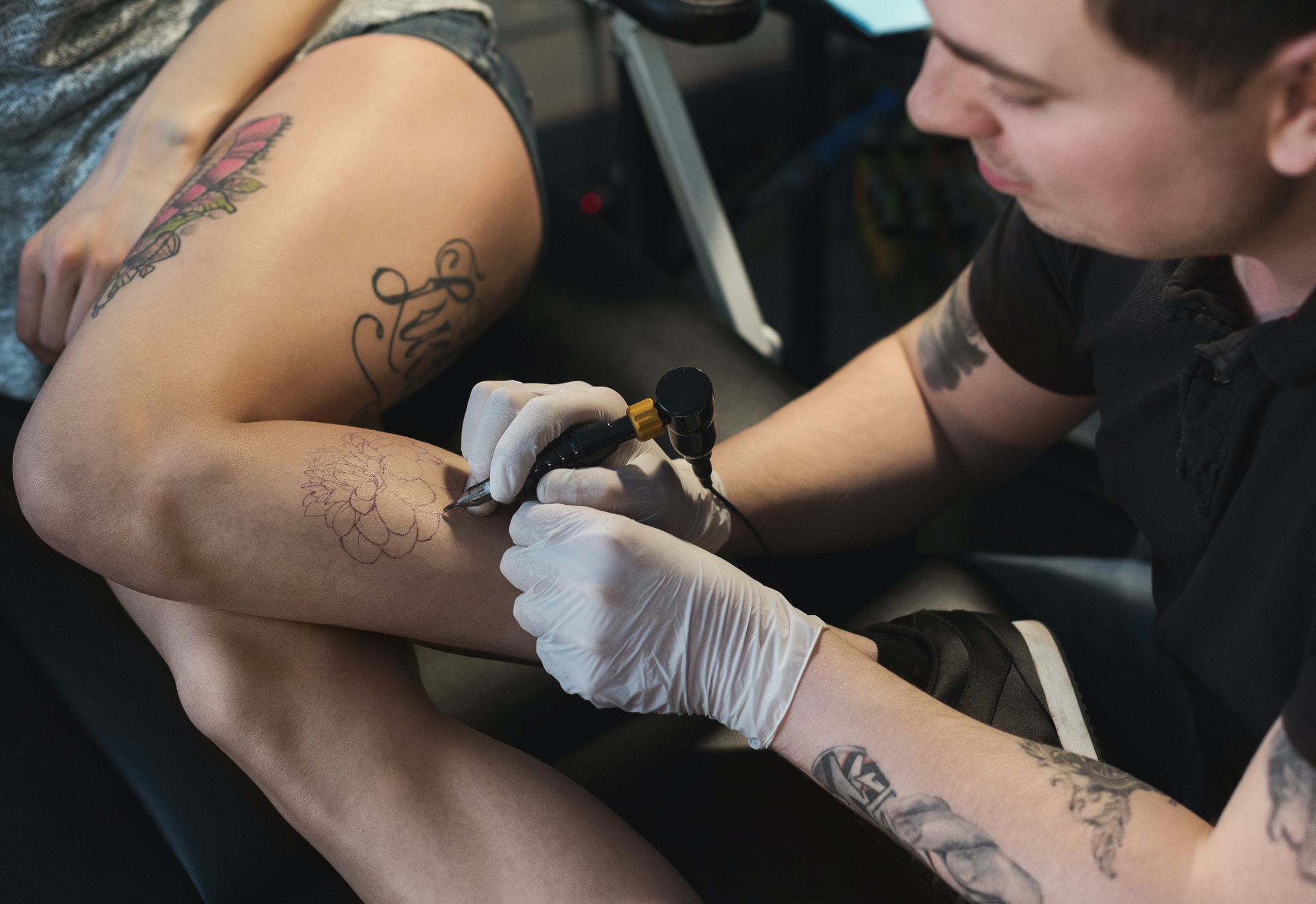 Professional tattoo artist making tattoo on leg